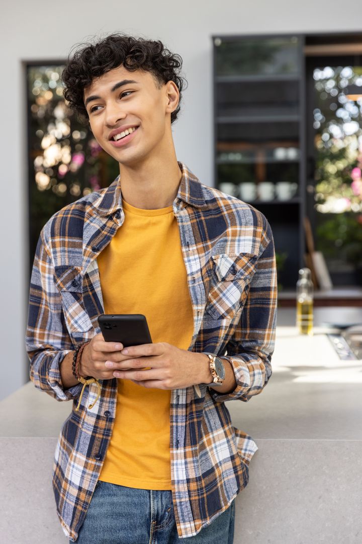 Young Man Relaxing in Modern Kitchen with Smartphone