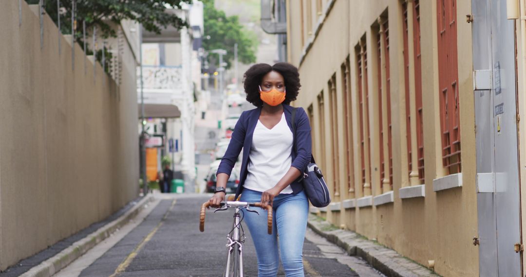 African American Woman Cycling Through Urban Street with Protective Mask - Free Images, Stock Photos and Pictures on Pikwizard.com