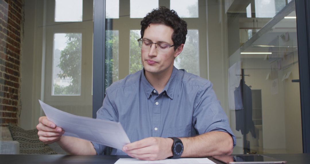 Focused Man Analyzing Documents in Modern Office Meeting Room - Free Images, Stock Photos and Pictures on Pikwizard.com