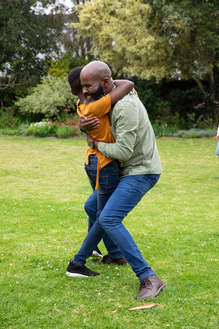 Father Hugging Child in Park Celebrating Family Bonding
