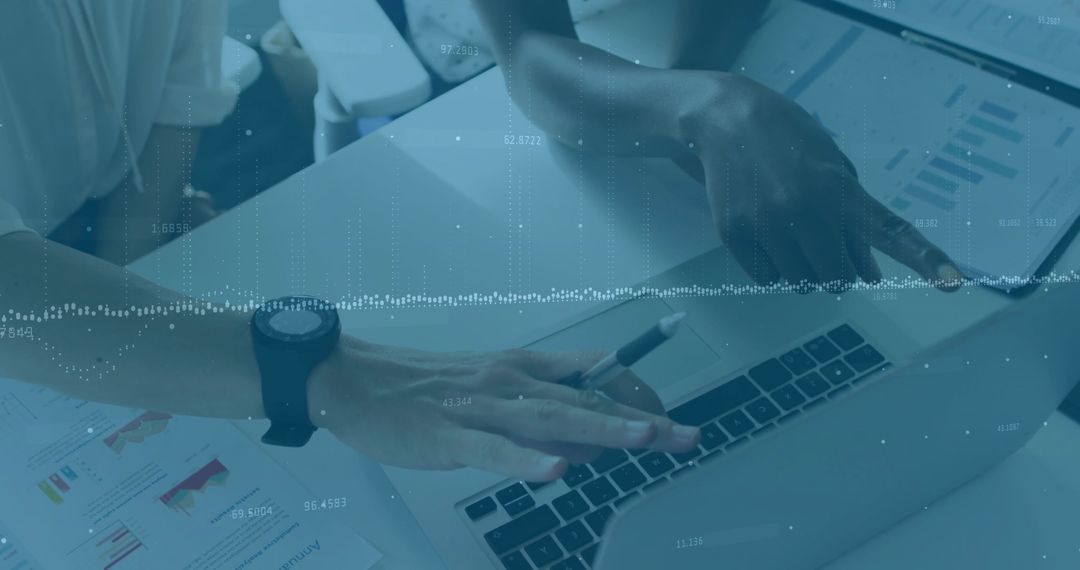Collaborating on data analysis with laptop, charts and printed reports in modern office
