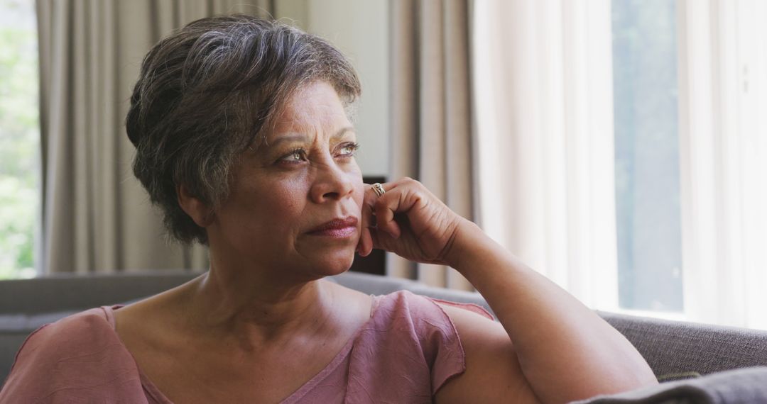 Thoughtful senior African American woman gazing out window - Free Images, Stock Photos and Pictures on Pikwizard.com