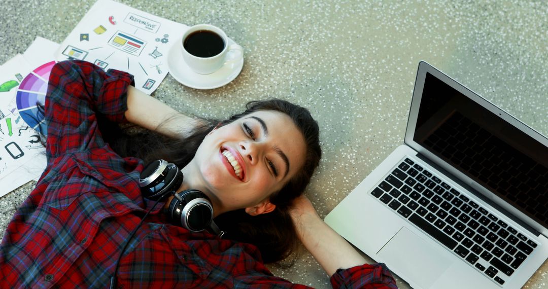 Happy Woman Lying on Floor with Laptop, Headphones, and Coffee - Free Images, Stock Photos and Pictures on Pikwizard.com