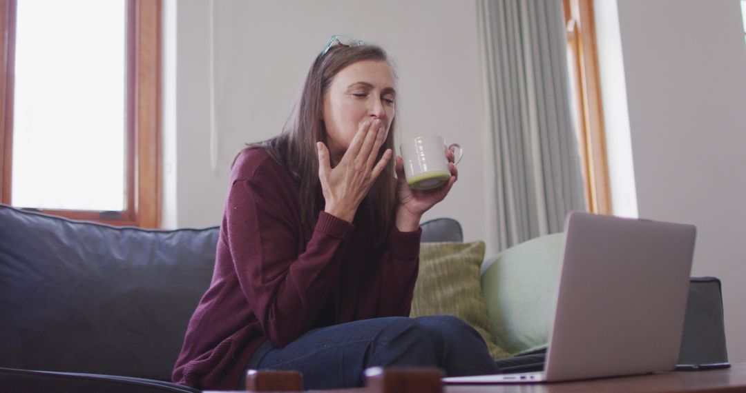 Woman Drinking Tea Yawning Sitting on Sofa - Free Images, Stock Photos and Pictures on Pikwizard.com