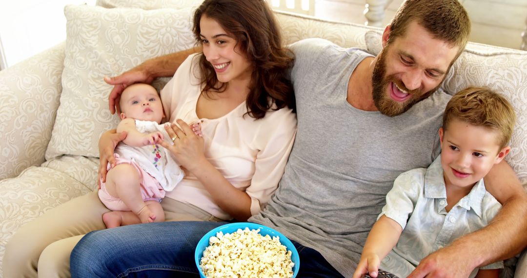 Happy Family Relaxing on Couch with Popcorn and Remote Control - Free Images, Stock Photos and Pictures on Pikwizard.com