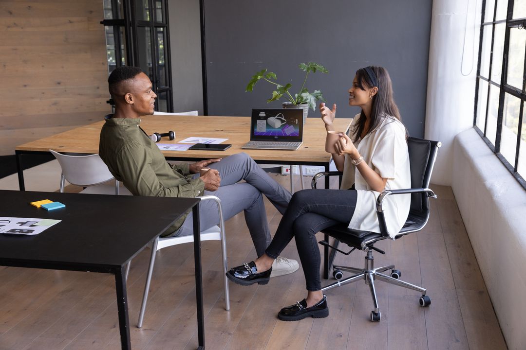 Diverse Colleagues Engaging in Productive Office Discussion with Laptop