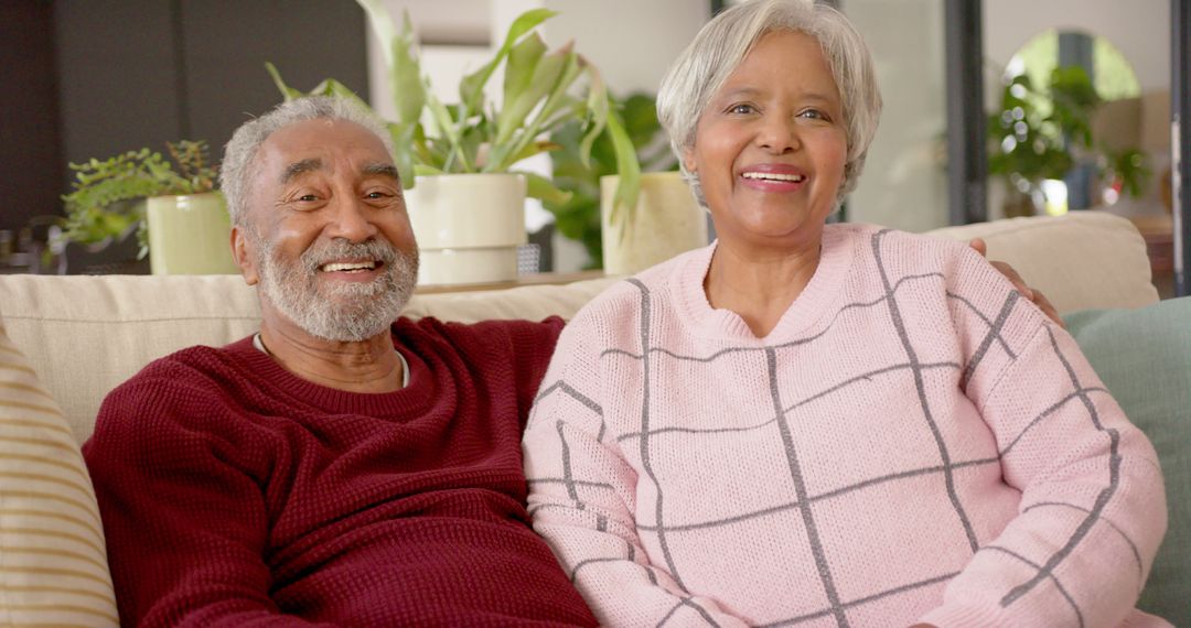 Happy Senior Couple Relaxing on Couch at Home with Plants in Background - Free Images, Stock Photos and Pictures on Pikwizard.com