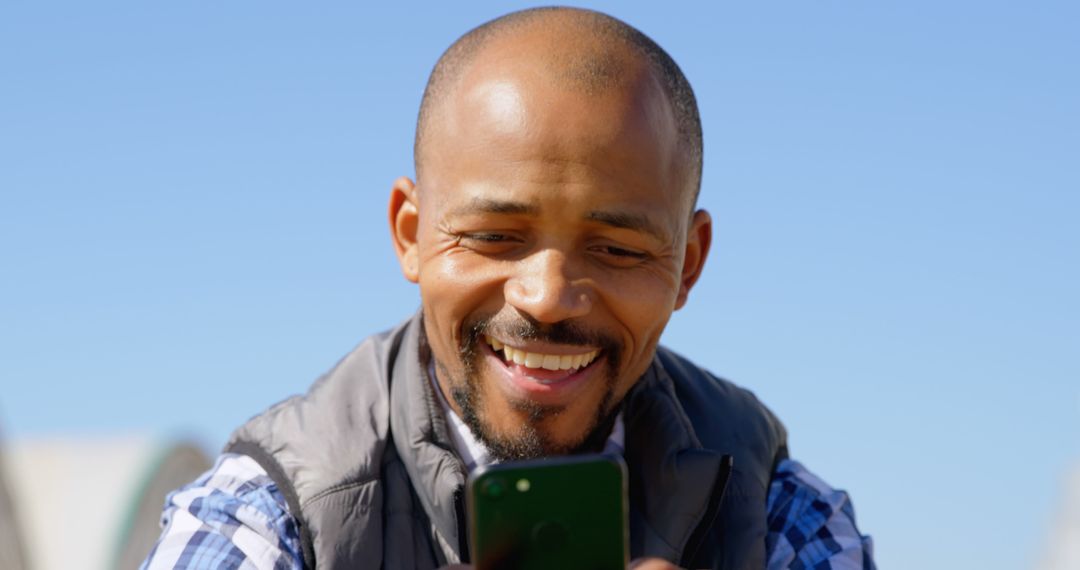 Smiling Man Using Smartphone Outdoors on Sunny Day - Free Images, Stock Photos and Pictures on Pikwizard.com