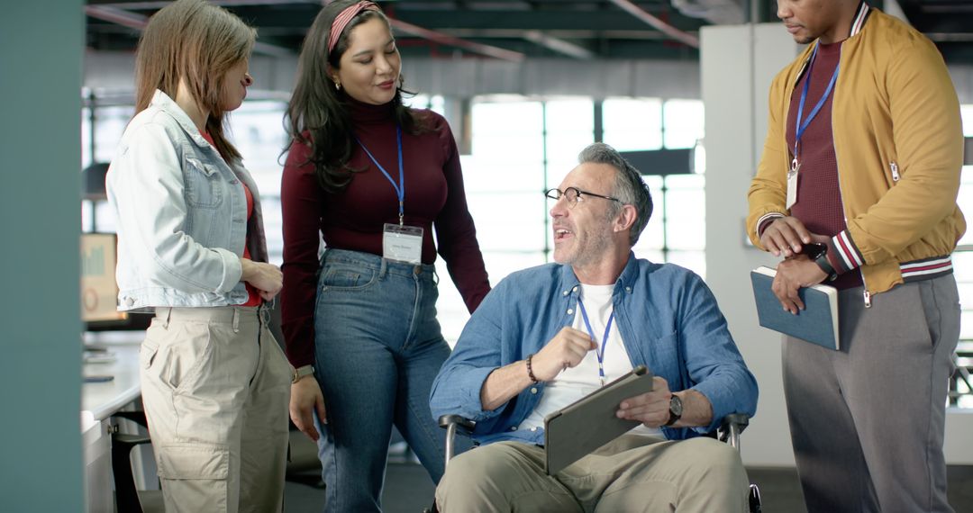 Inclusive team collaborating with wheelchair user in modern open-plan office, casual teamwork