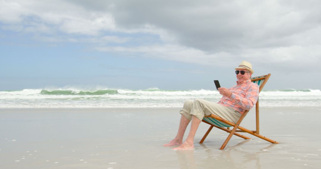 Senior Man Relaxing with Smartphone on Beach Chair by Sea - Free Images, Stock Photos and Pictures on Pikwizard.com