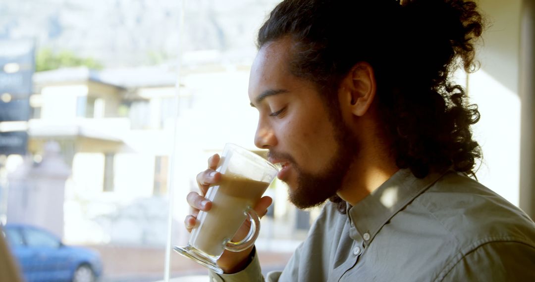 Young Man Savoring Hot Beverage by Sunny Window - Free Images, Stock Photos and Pictures on Pikwizard.com