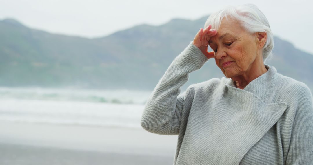 Elderly Woman Reflecting By The Beach On An Overcast Day - Free Images, Stock Photos and Pictures on Pikwizard.com