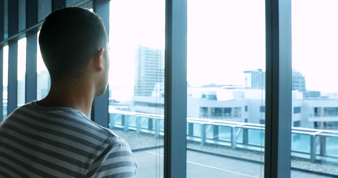 Man Looking Out Office Window at Urban Cityscape - Free Images, Stock Photos and Pictures on Pikwizard.com