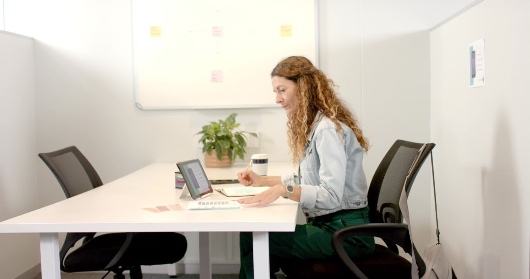 Mature Woman Working in Office with Notebook and Tablet
