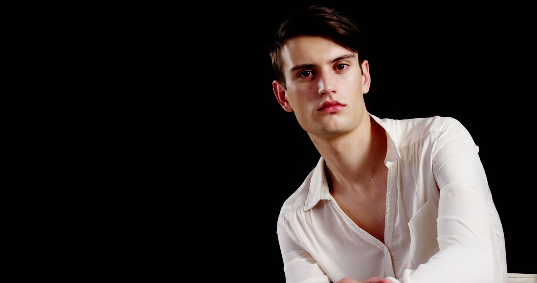 Confident Young Man Wearing White Shirt Against Black Background - Free Images, Stock Photos and Pictures on Pikwizard.com