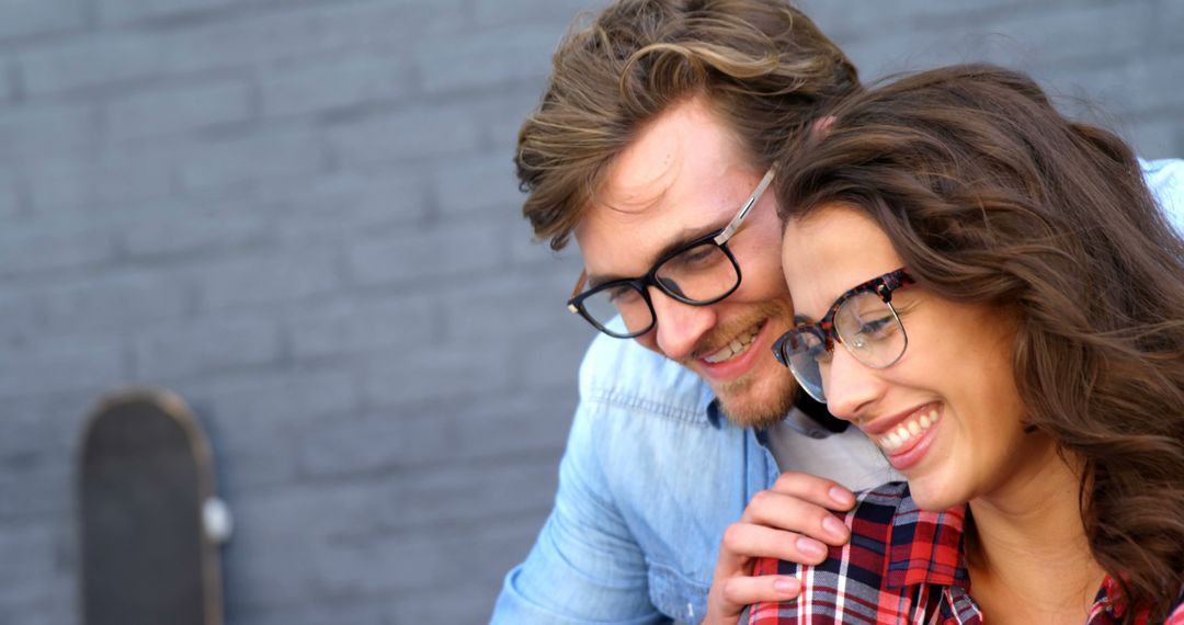 Smiling Couple with Glasses Embracing Outdoors on Sunny Day