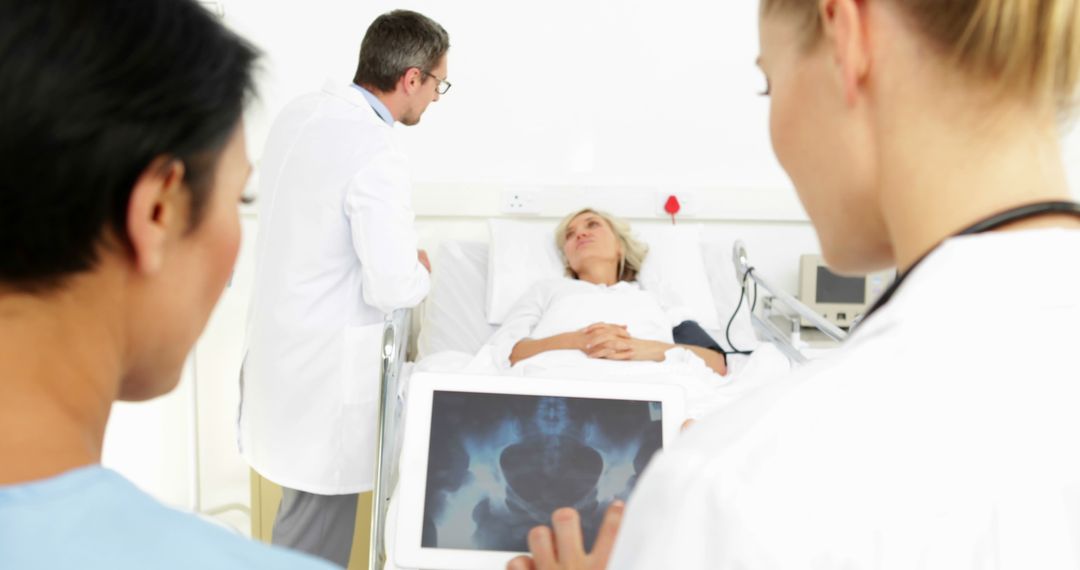 Doctors Discussing Patient X-ray at Hospital Bedside - Free Images, Stock Photos and Pictures on Pikwizard.com