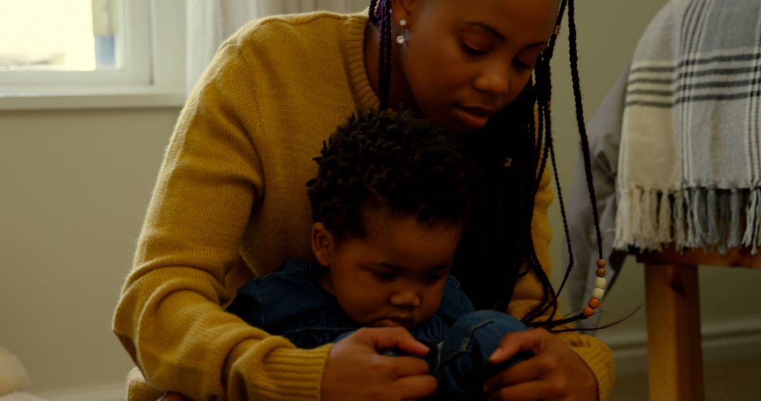 Mother Dressing Her Toddler in Denim Overalls at Home - Free Images, Stock Photos and Pictures on Pikwizard.com