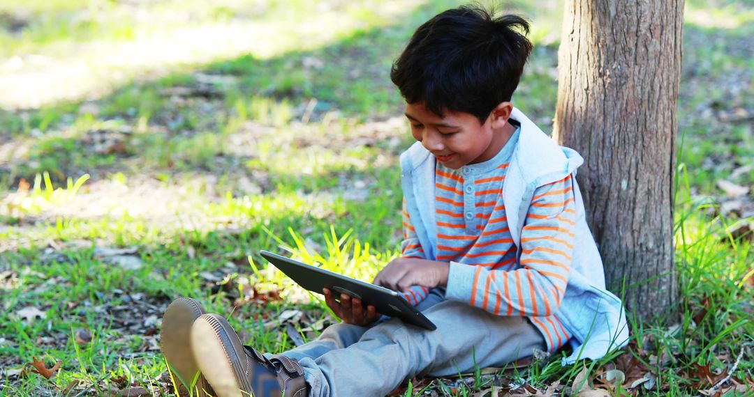 Young Boy Using Tablet Outdoor in Autumn Park - Free Images, Stock Photos and Pictures on Pikwizard.com