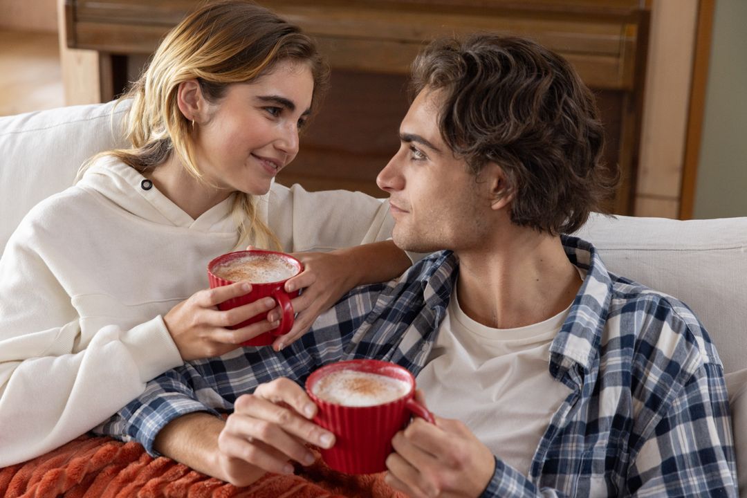 Young Couple Enjoying Warm Drinks on Cozy Couch