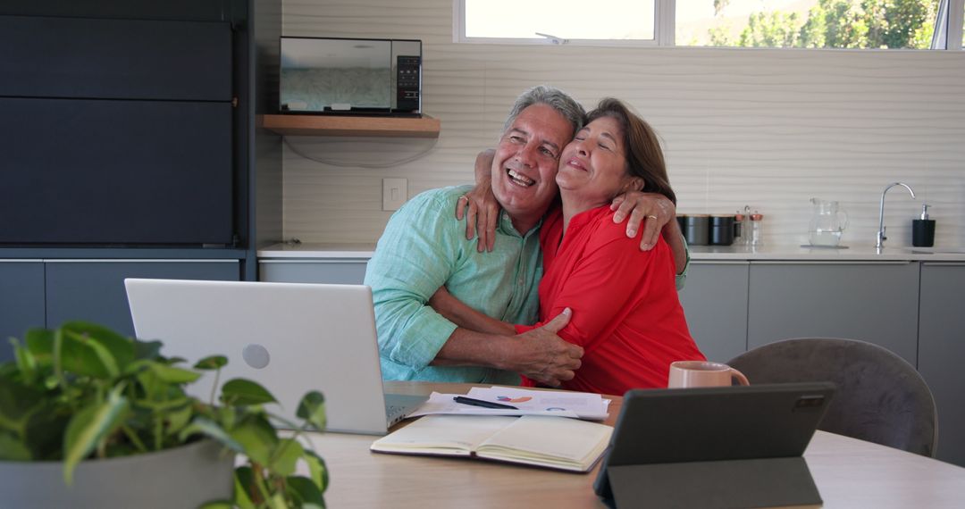 Senior Couple Embracing While Planning with Devices