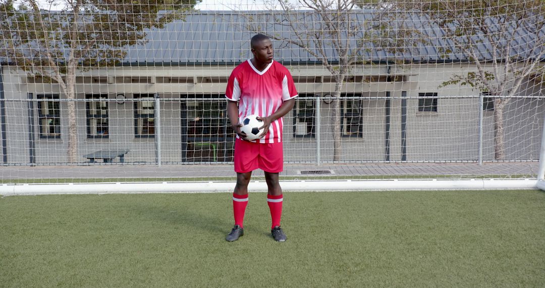 Goalkeeper Holding Soccer Ball Standing Before Goal Net