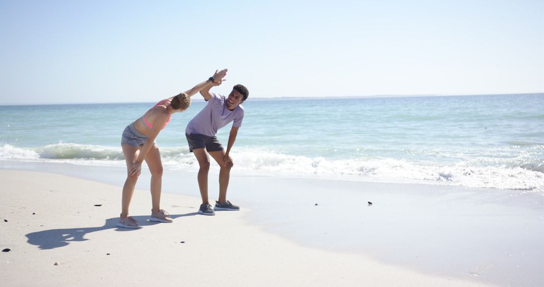 Couple Stretching on Sandy Beach with Ocean Backdrop