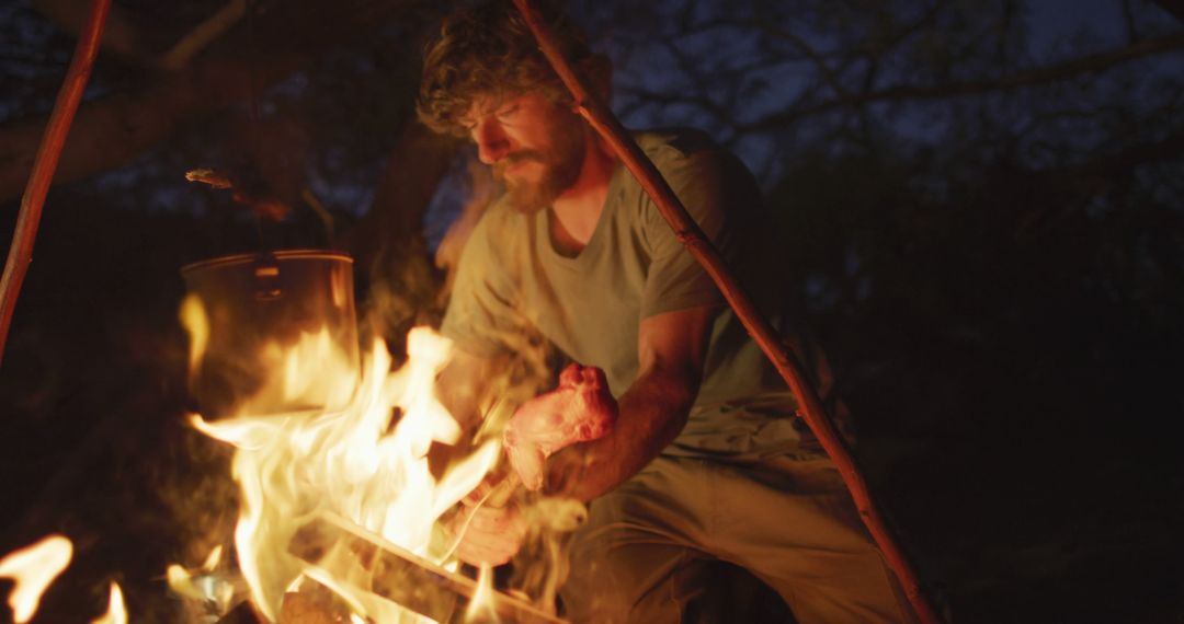 Man Cooking Food Over Campfire at Night in Wilderness - Free Images, Stock Photos and Pictures on Pikwizard.com