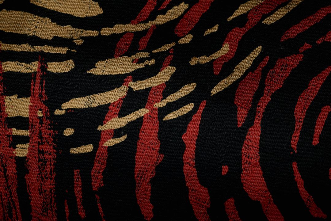 Textured Black Fabric with Abstract Red and Gold Brushstroke Animal Print Pattern