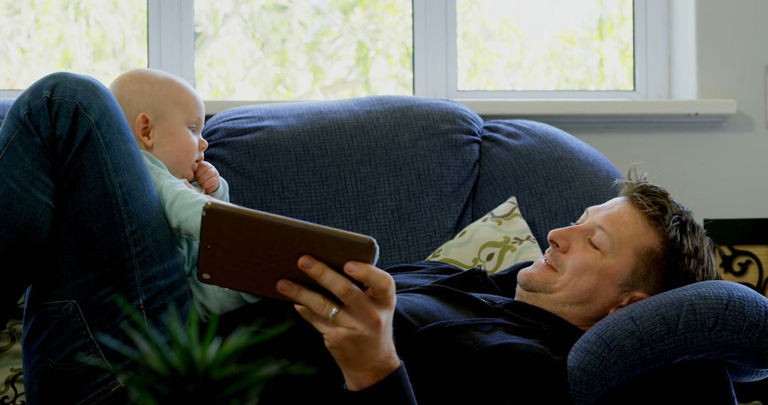 Father Relaxing with Baby on Couch While Using Tablet - Free Images, Stock Photos and Pictures on Pikwizard.com