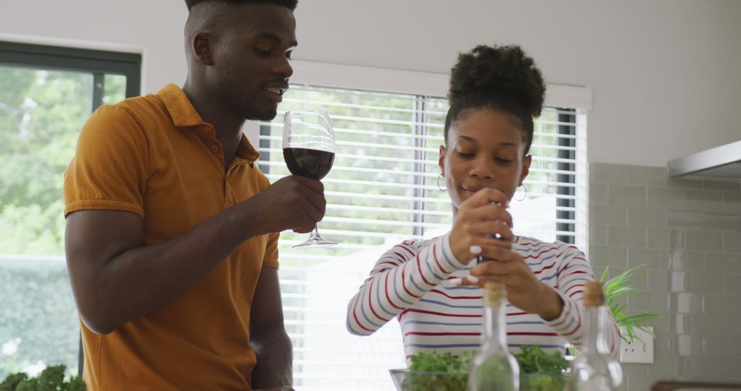 Image of happy african american couple cooking together in kitchen with wine - Free Images, Stock Photos and Pictures on Pikwizard.com