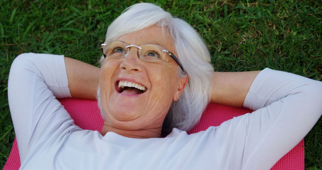 Happy Elderly Woman Relaxing on Grass Outdoors - Free Images, Stock Photos and Pictures on Pikwizard.com