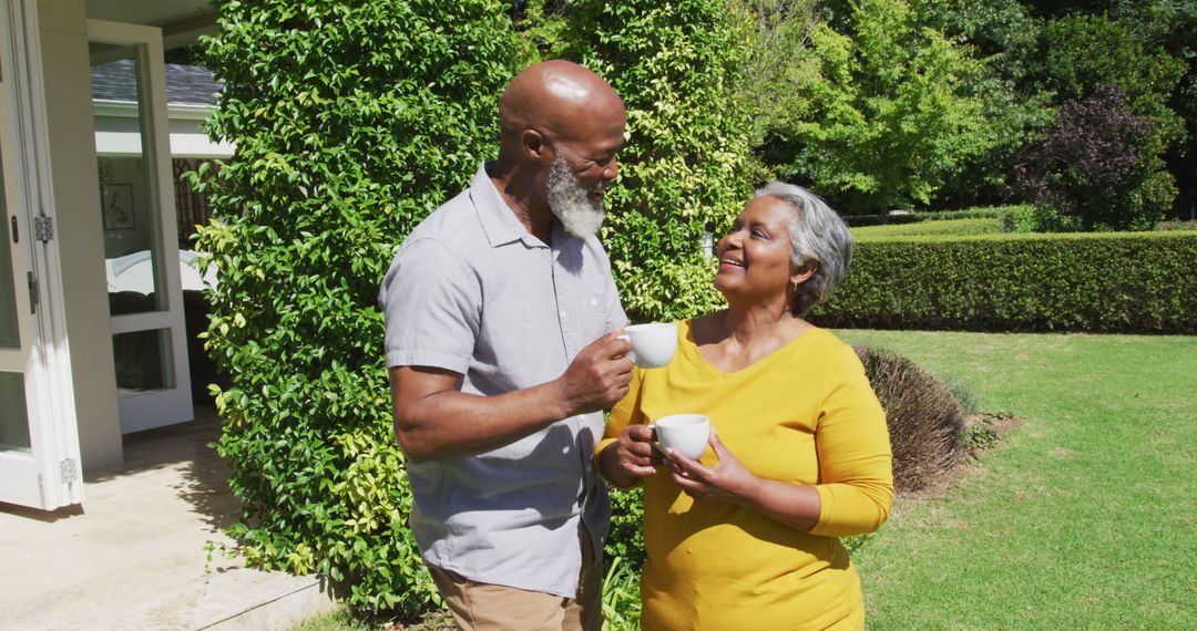 Senior african american couple talking and holding cups of tea in sunny garden - Free Images, Stock Photos and Pictures on Pikwizard.com
