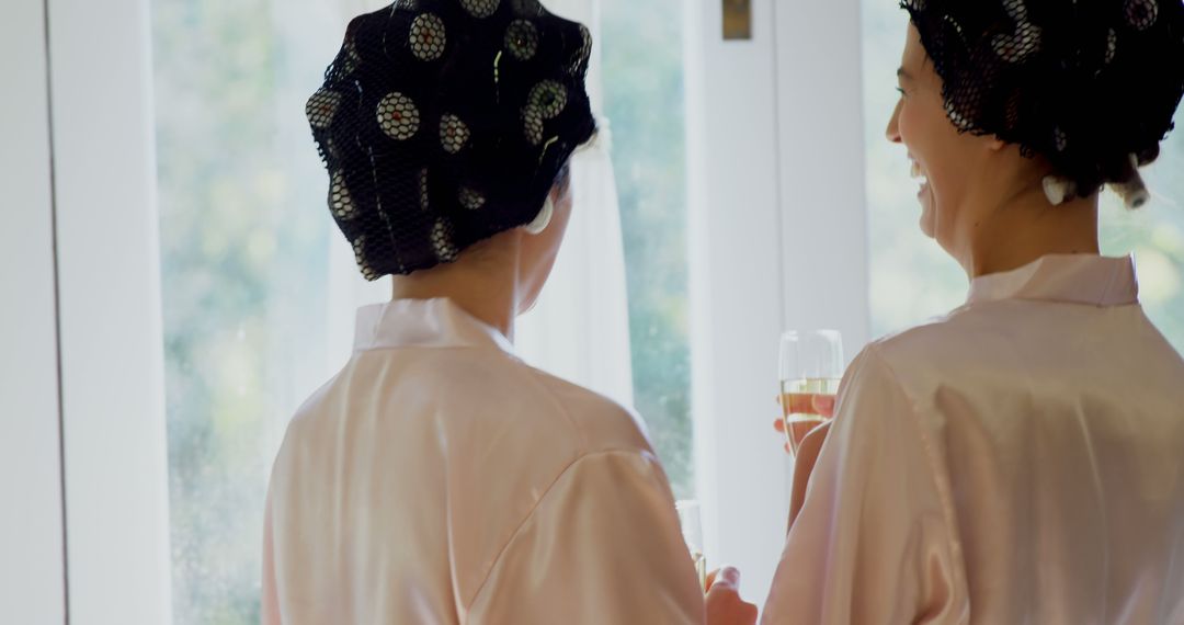 Two Women in Robes with Hair Rollers Enjoying Drinks - Free Images, Stock Photos and Pictures on Pikwizard.com