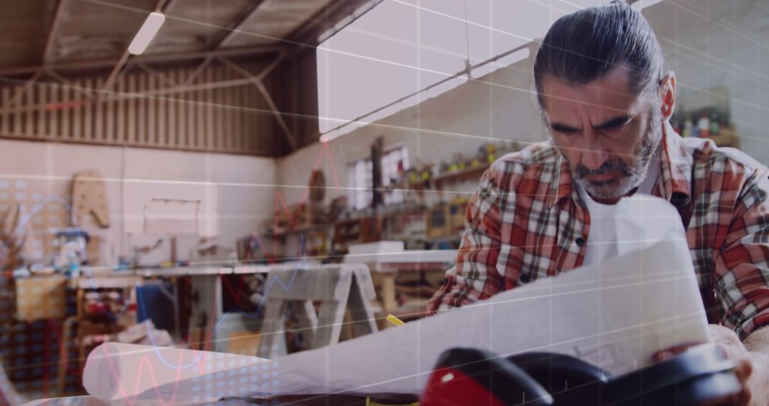 Carpenter Analyzing Plans in Workshop with Digital Overlay