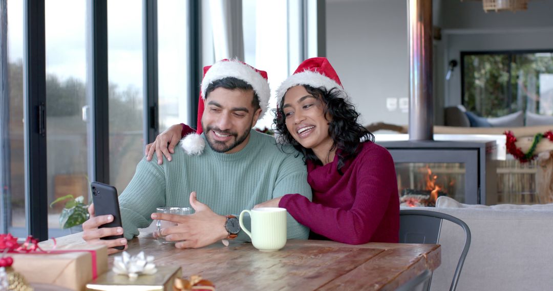 Couple Wearing Santa Hats Video Chatting on Smartphone at Home - Free Images, Stock Photos and Pictures on Pikwizard.com