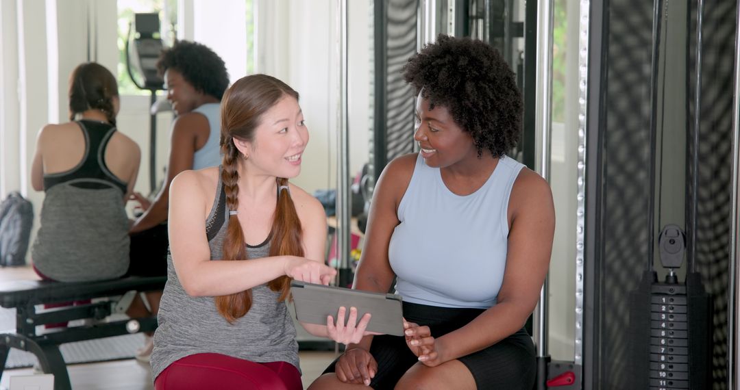 Fitness Trainer Using Tablet with Client in Gym Setting
