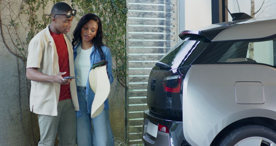 Couple Examining Electric Hatchback and Discussing via Smartphone