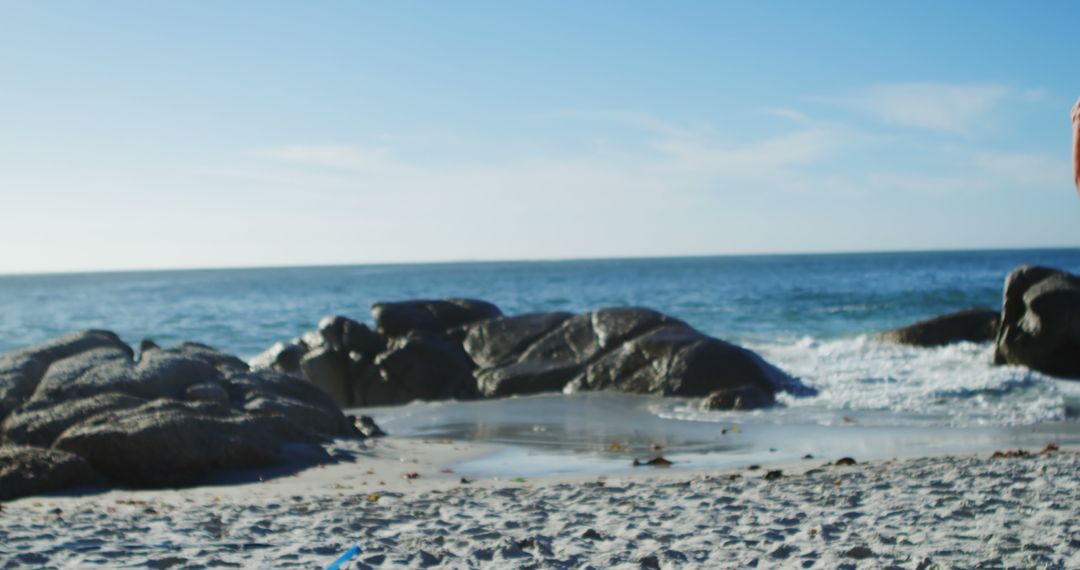 Calm Beach With Rocky Shoreline and Clear Sky - Free Images, Stock Photos and Pictures on Pikwizard.com