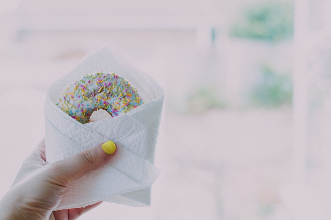 Hand Holding Delicious Sprinkle Donut Closeup