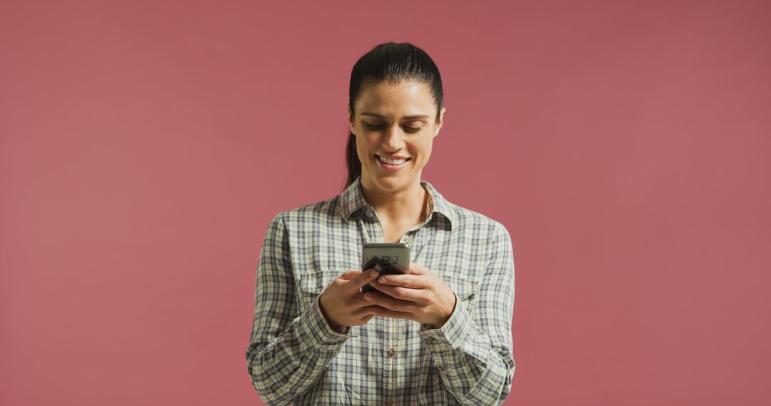 Smiling Woman Texting on Smartphone with Pink Background - Free Images, Stock Photos and Pictures on Pikwizard.com