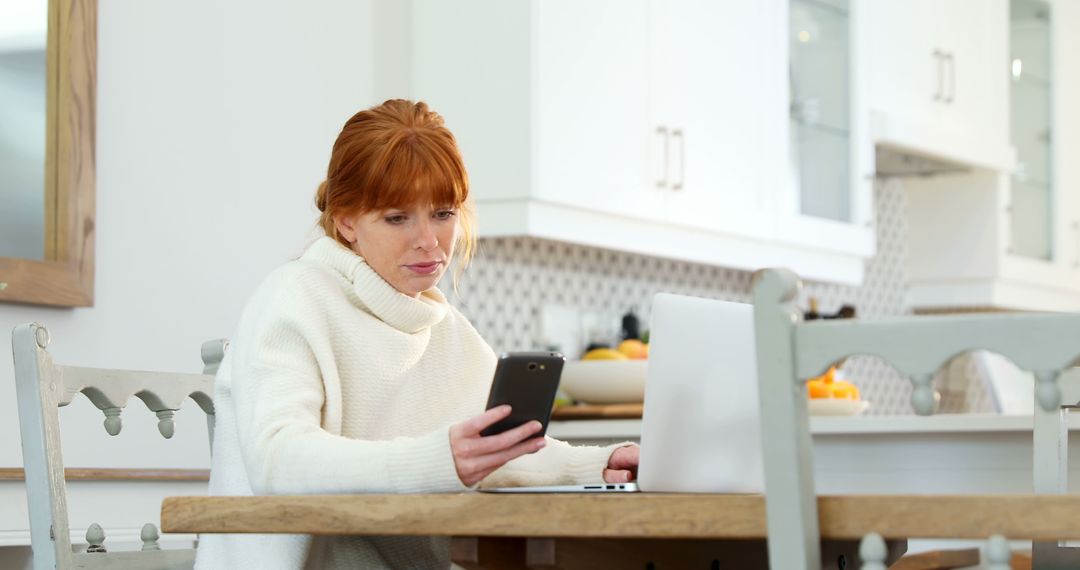 Woman Connected with Smartphone and Laptop in Bright Kitchen - Free Images, Stock Photos and Pictures on Pikwizard.com