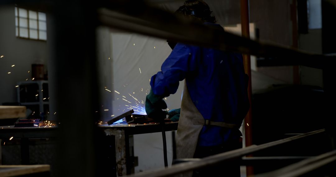 Industrial Worker Welding Metal in Dimly Lit Workshop - Free Images, Stock Photos and Pictures on Pikwizard.com