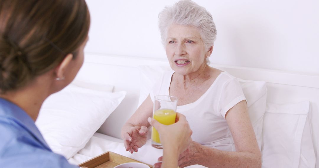 Nurse Assisting Elderly Woman in Bed with Glass of Juice - Free Images, Stock Photos and Pictures on Pikwizard.com