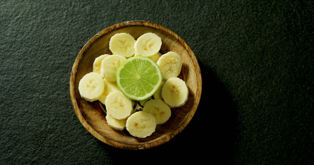 Sliced Bananas and Lime in Wooden Bowl on Dark Surface - Free Images, Stock Photos and Pictures on Pikwizard.com