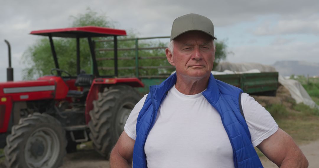 Confident Senior Farmer Standing by Tractor in Rural Field - Free Images, Stock Photos and Pictures on Pikwizard.com