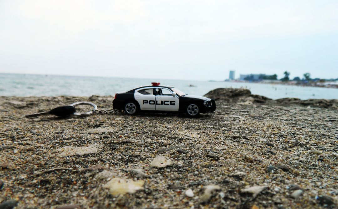 Model Police Car Keychain on Rocky Beach Shoreline - Free Images, Stock Photos and Pictures on Pikwizard.com