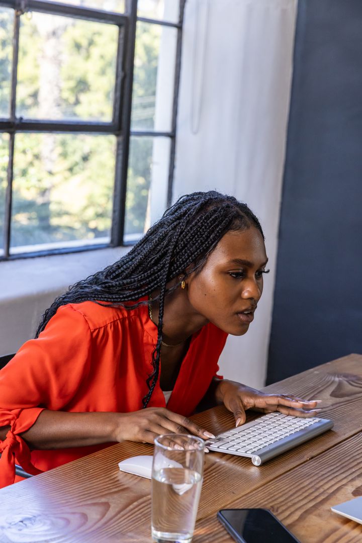 Focused Professional Woman Analyzing Computer Screen at Modern Workspace