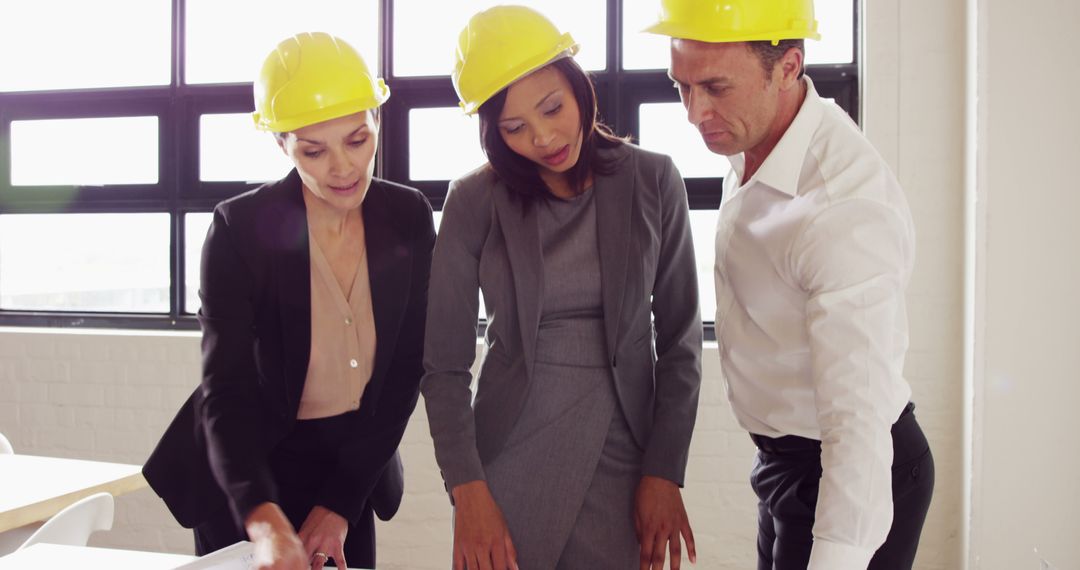 A multicultural team of construction professionals discusses plans intently. - Free Images, Stock Photos and Pictures on Pikwizard.com