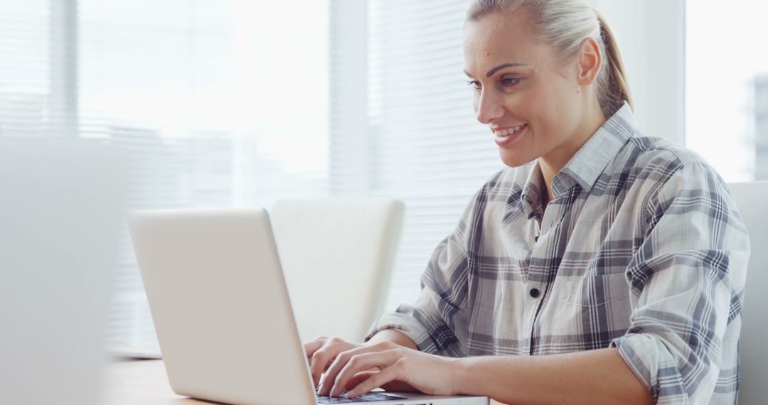 Smiling Woman Working on Laptop in Modern Office